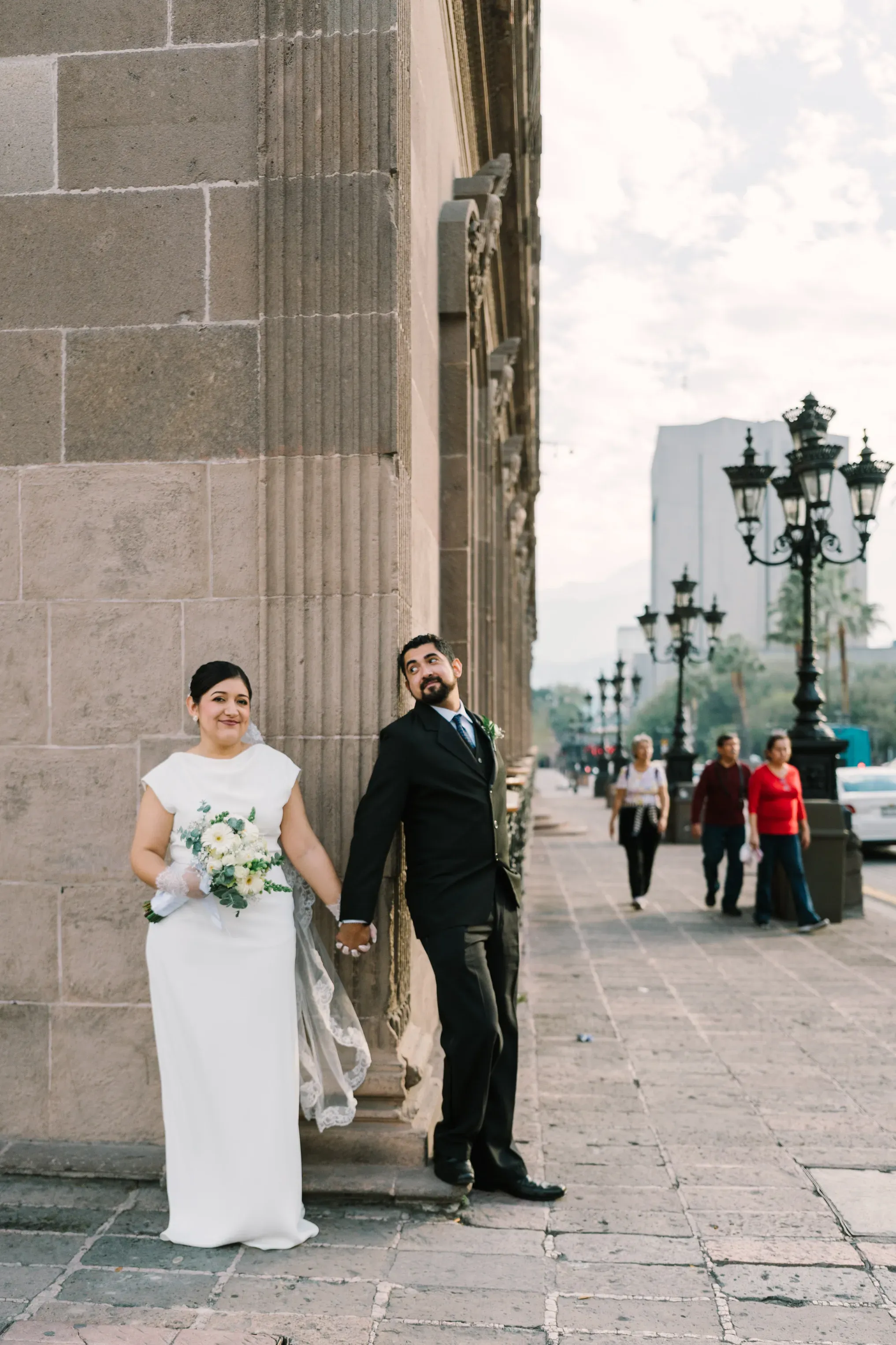 Pareja de recién casados posando junto a columna de piedra en calle histórica de Monterrey