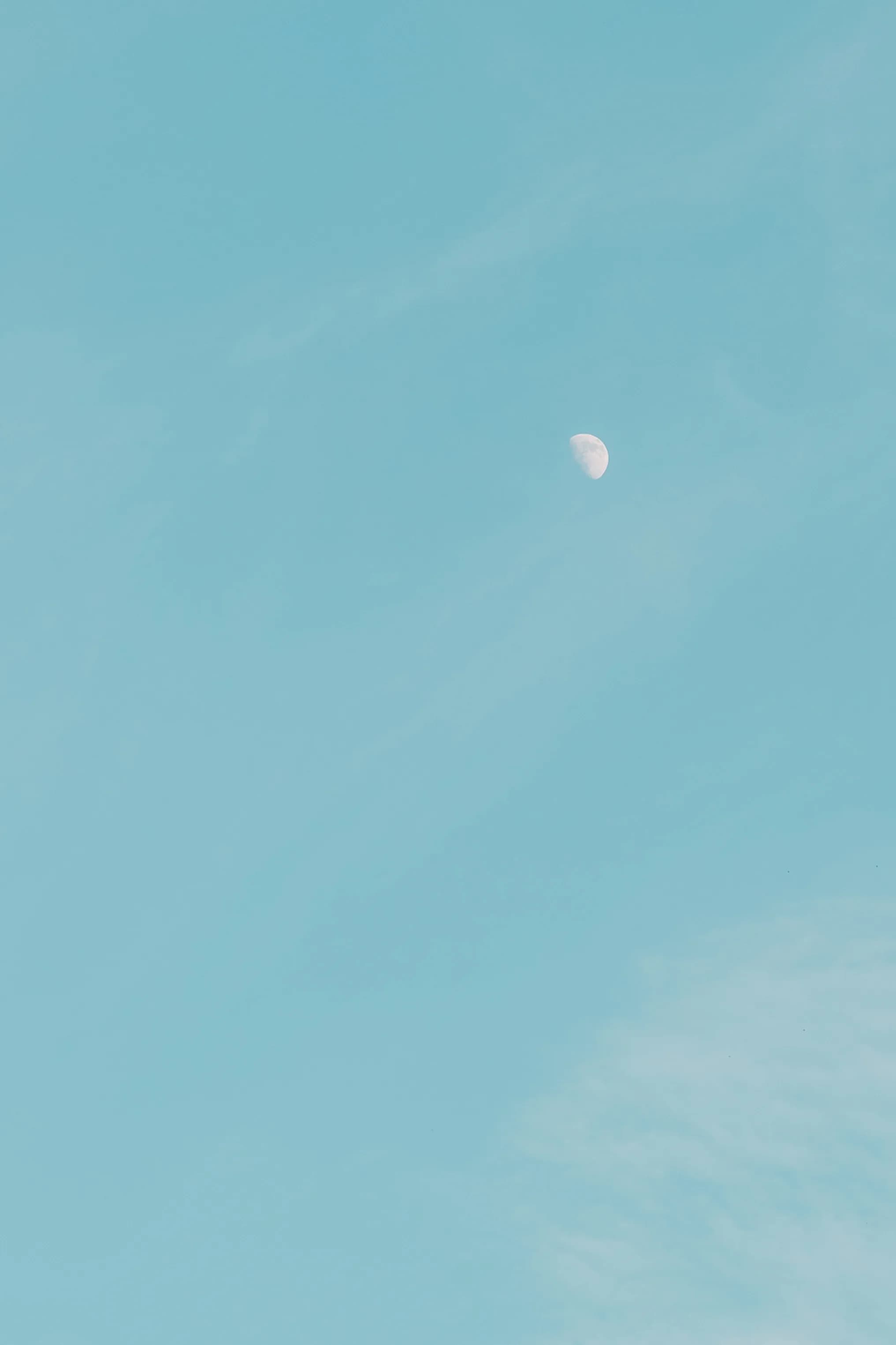 Luna en cuarto creciente en cielo azul turquesa despejado durante el día