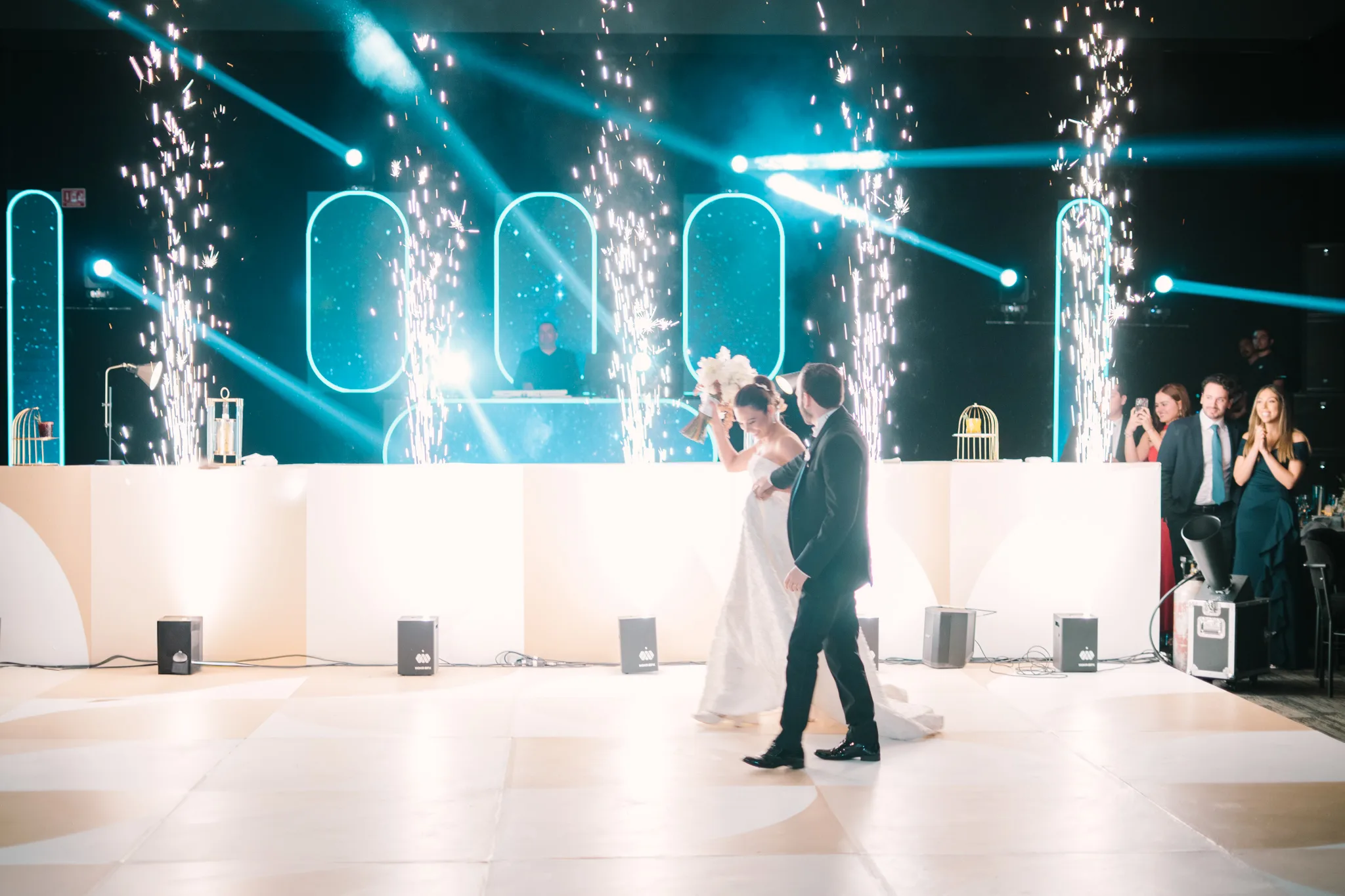 Pareja de novios bailando con fuentes de chispas y luces de escenario en recepción de boda